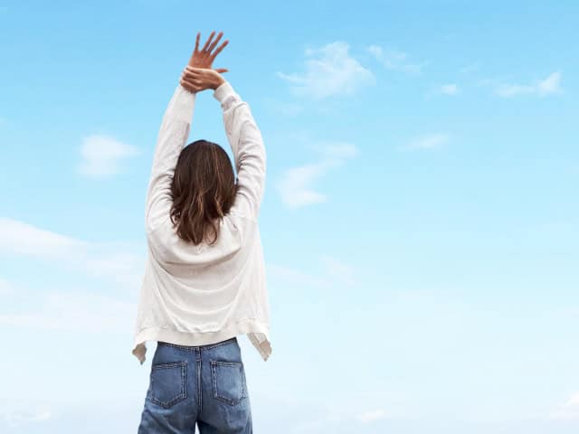 背伸びをする女性の後ろ姿