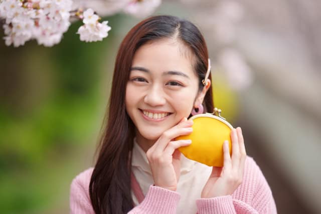 黄色い財布を手に持つ女性