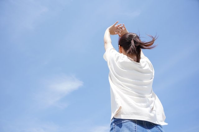 空に向かって伸びをする女性